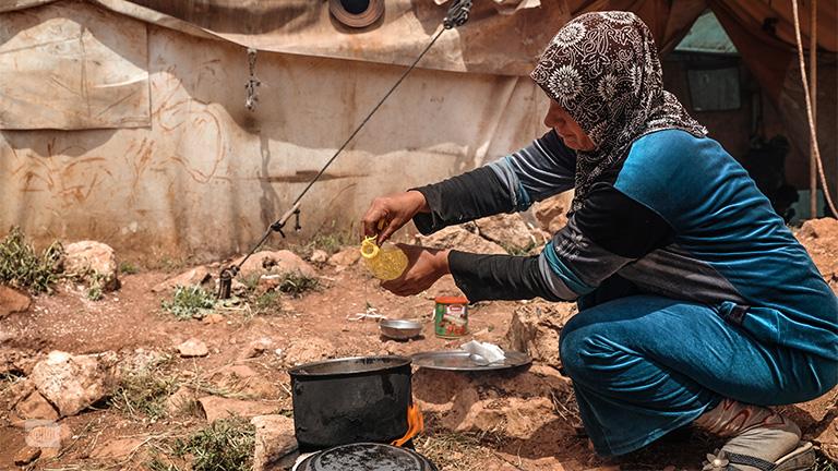 تطهو طعام أسرتها على موقد بسيط صنعته بيديها